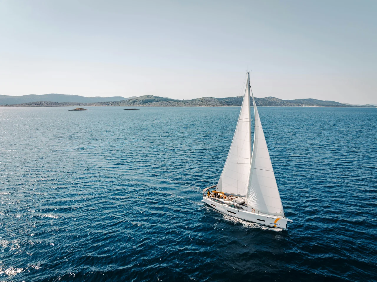 A white sailboat crossing blue water among the Kornati islands