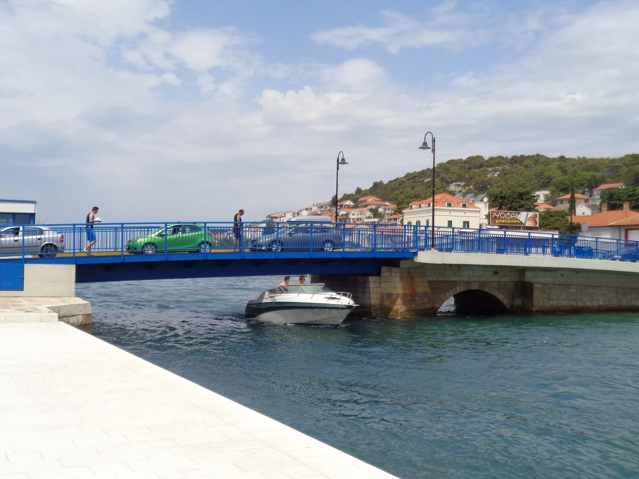 Motorboat beneath the blue movable bridge in Tisno